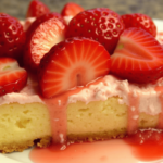 A slice of strawberry cheesecake dump cake topped with fresh strawberries and drizzled with strawberry sauce.